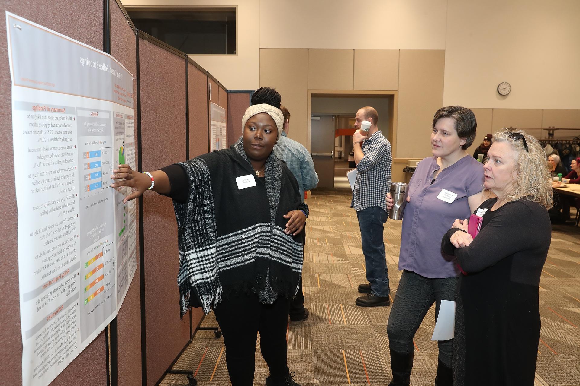 Dr. Margaret Weinberger (left) director of Undergraduate Studies in sociology with students during a research poster review.