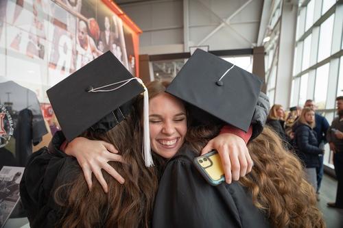 一个人在毕业典礼上拥抱两个即将毕业的学生
