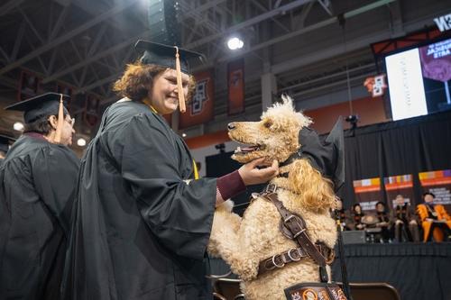 学生在毕业典礼上拥抱服务犬